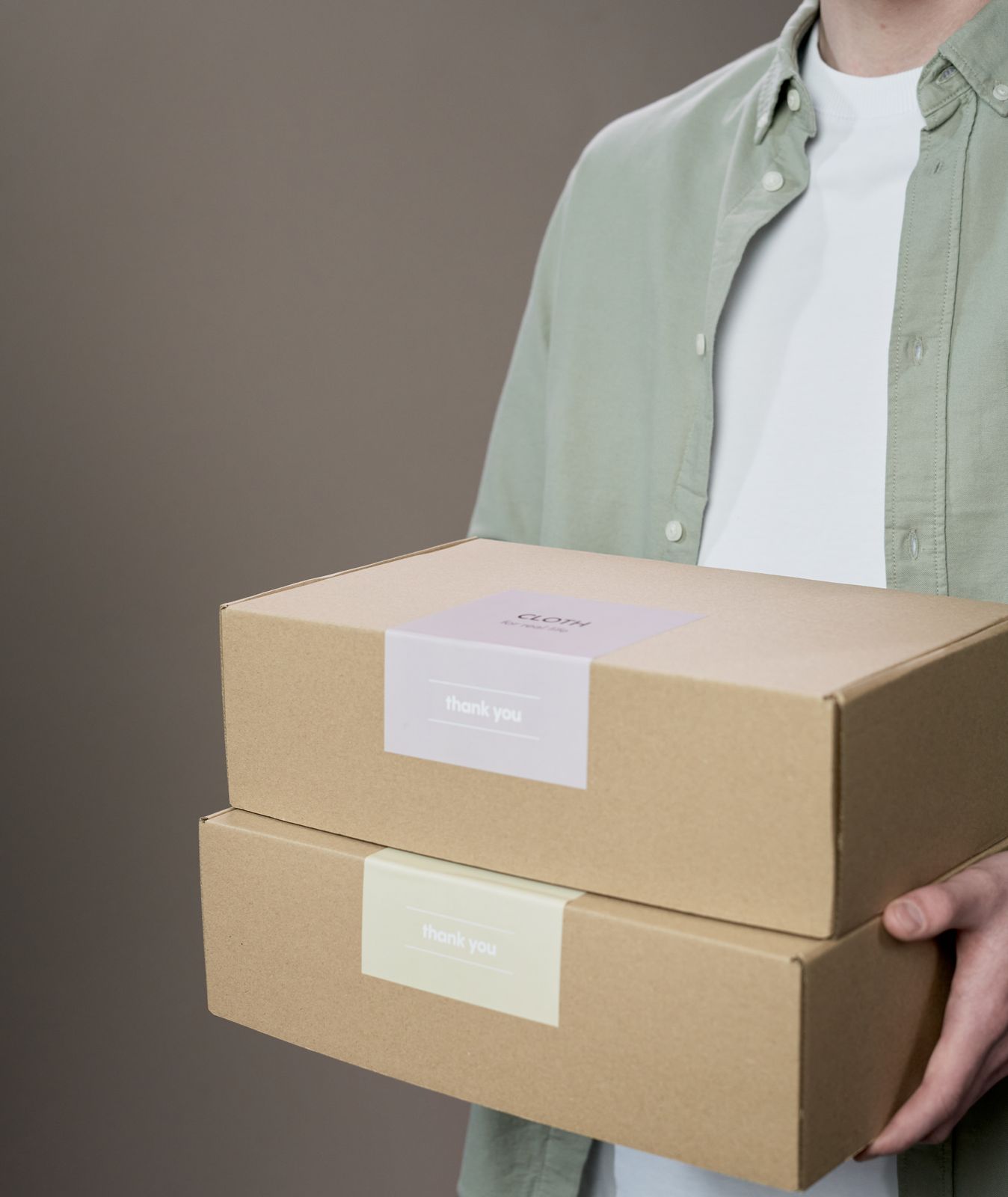 A person in a sage shirt carrying two carefully packed orders.